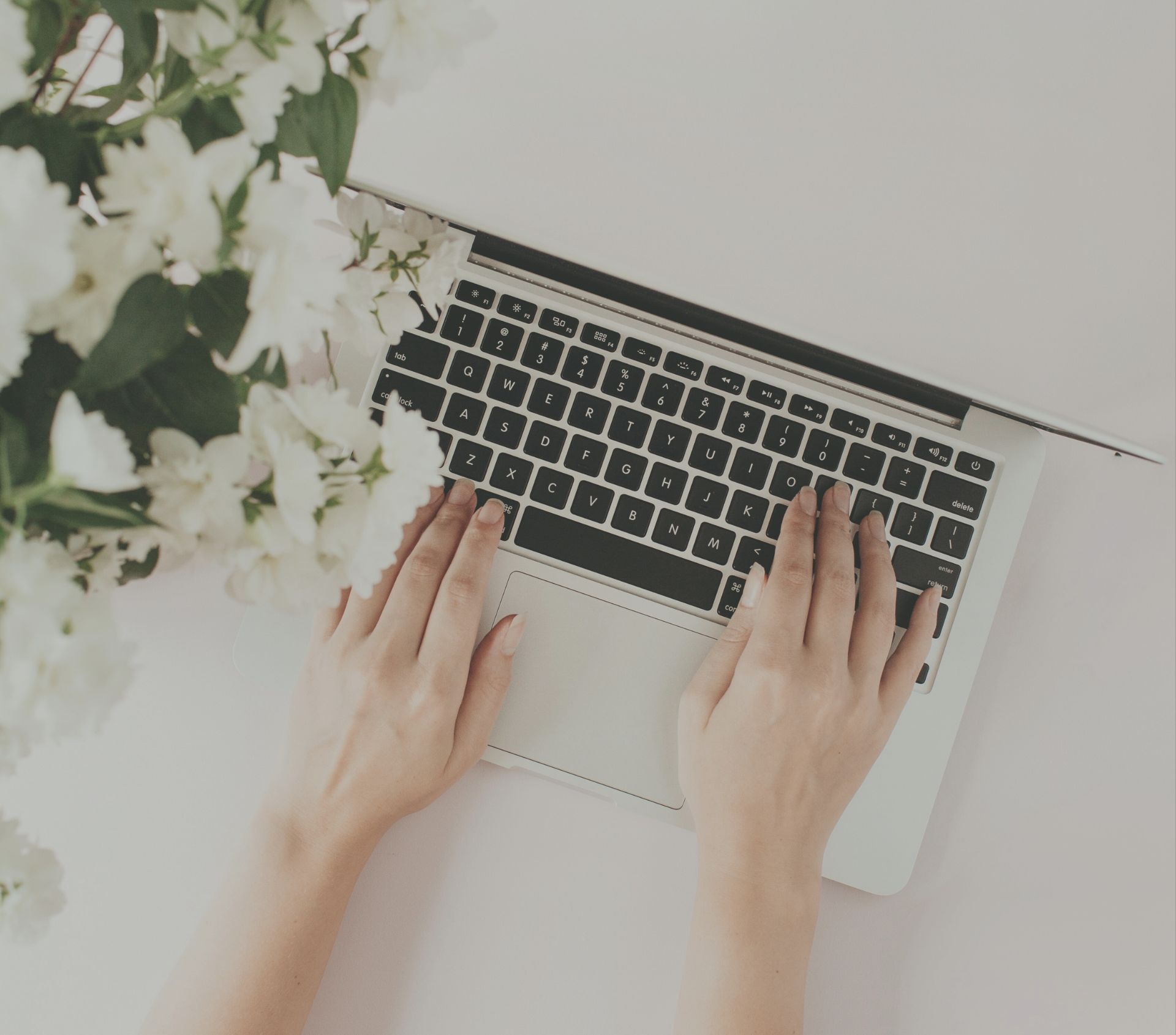 En virtuell assistents händer på en laptop med blommor