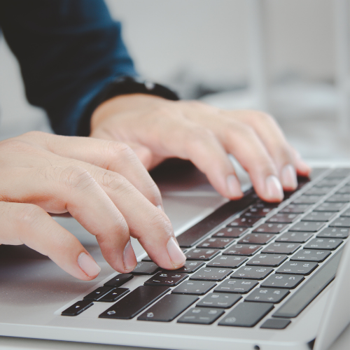 Ett par händer på en laptop som utför administrativt arbete online